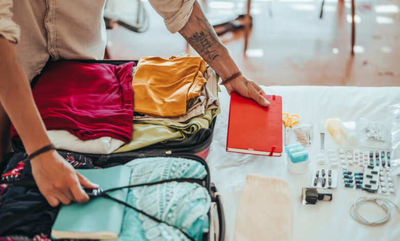 An unrecognizable man packs clothes and all the necessities for traveling in a suitcase.