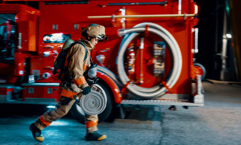 Firefighter running with a hose next to a fire engine before or after an emergency