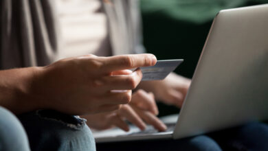 Paying money and buying online concept, couple doing internet shopping with computer, customers making secure payment on laptop via e-banking service, close up view of hand holding credit card