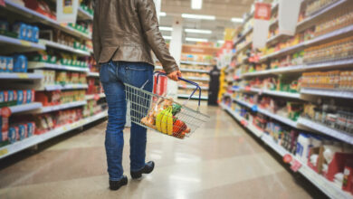 Cropped shot of a woman holding a basket while shopping at a grocery store